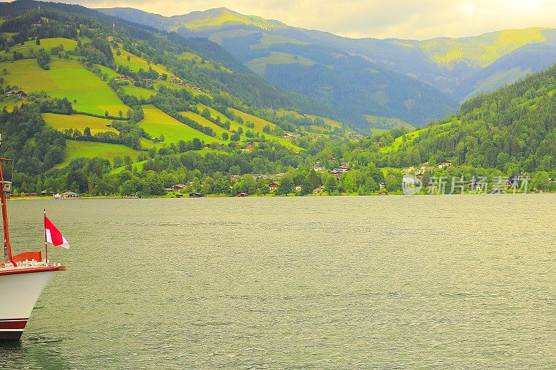 船漂浮在美丽的泽勒湖和奥地利国旗-泽尔am See和山脉景观，Tirol Salzburger土地，奥地利